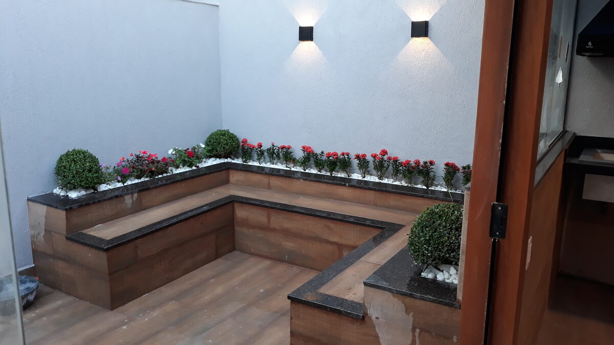 Canteiro com flores, arbustos podados e iluminação de destaque